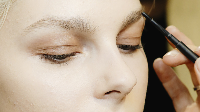 Automatic eyebrow pencil being applied to blonde eyebrows