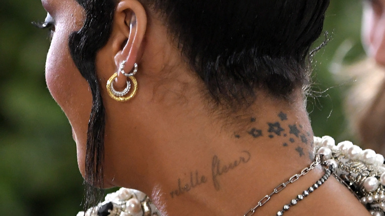 Rihanna's neck tattoo says "rebelle fleur"