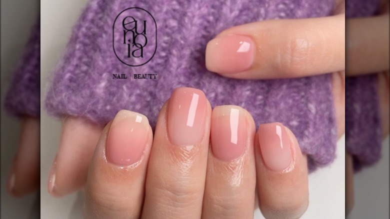 Neutral pink ombré nails against purple sweater