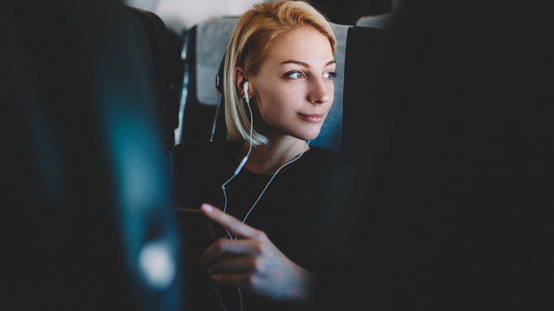 Woman wearing headphones on airplane 