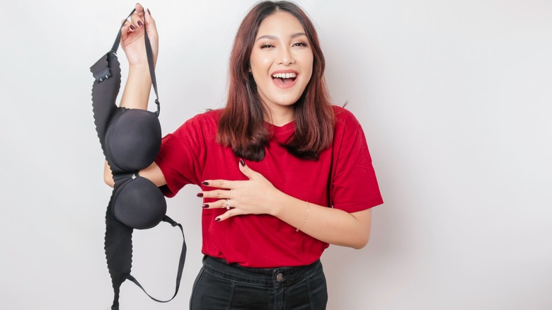 Woman smiling and holding black bra 