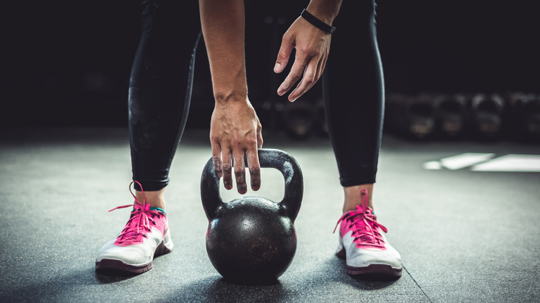 Athletic woman picking a kettlebell from the floor 