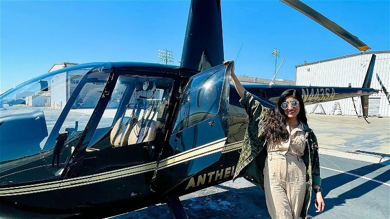 Brunette woman standing next black helicopter
