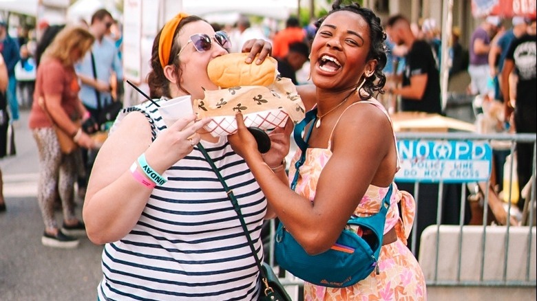 Two women laughing eating street food