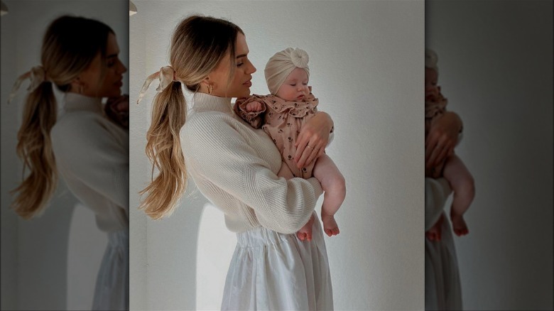 Woman dressed in cream holding a baby