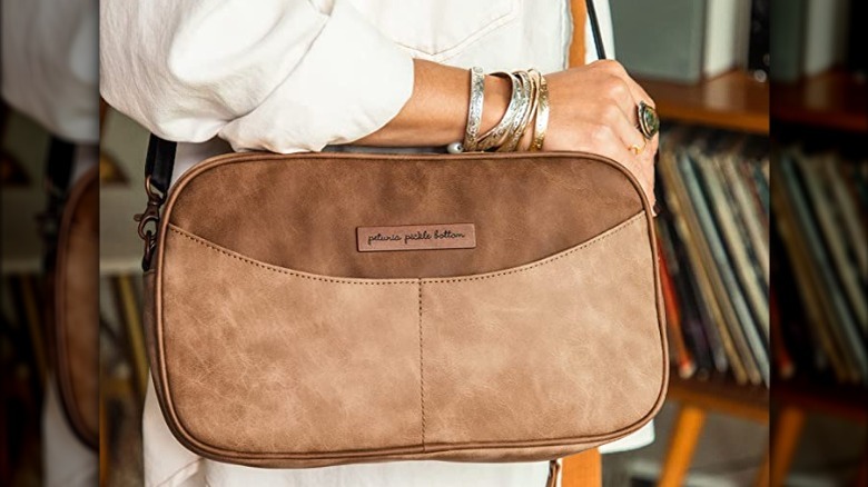 person holding tan crossbody bag