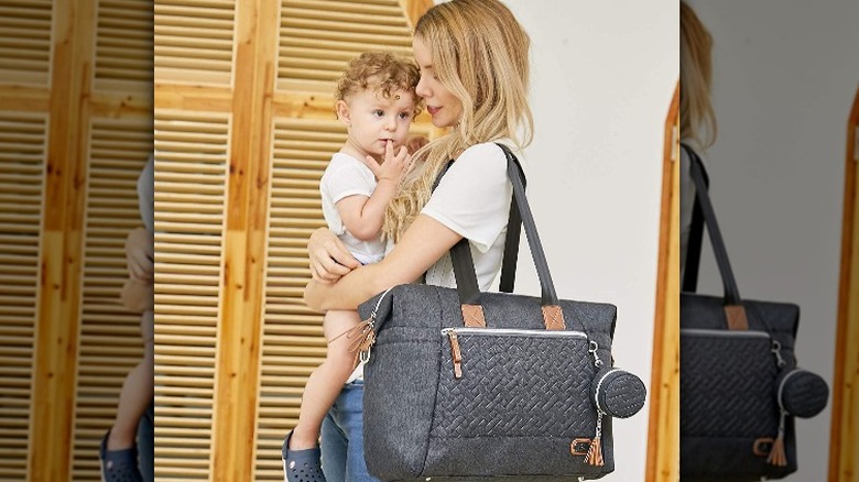 woman holding young child and carrying grey bag