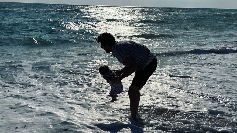 Chris McNally holding his baby at the beach