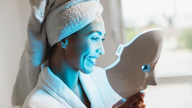 Woman using anti-acne blue LED light