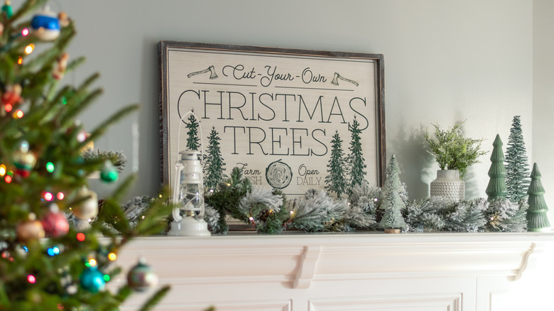 White mantel topped with Christmas tree farm word art 