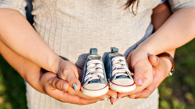 expecting couple holding sneakers