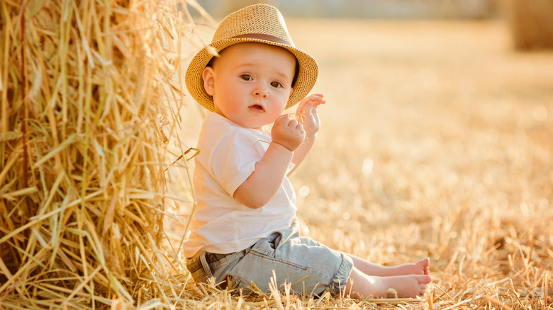 Baby in hat next to hay
