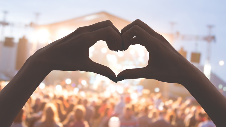 Someone throws up a heart at a music festival