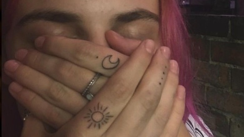 Person covering their mouth with tattooed hands