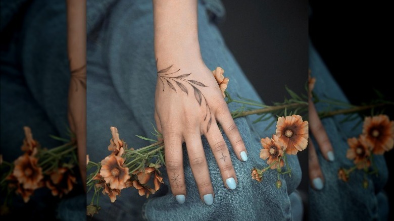 Hand with tattoo holding flowers