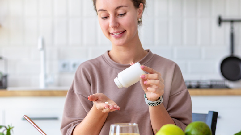 woman taking pill in kitchen