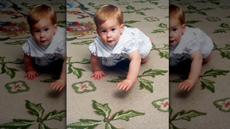 Prince Harry as a toddler crawling across the carpet