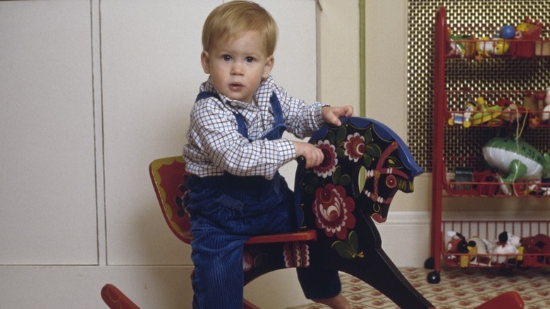 A young Prince Harry rides a rocking horse