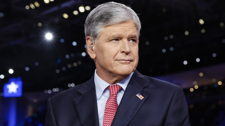 Sean Habbity wearing a blue suit and red tie with a serious expression on his face, highlighting his age