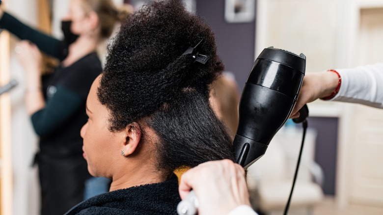 woman with getting hair heat-styled