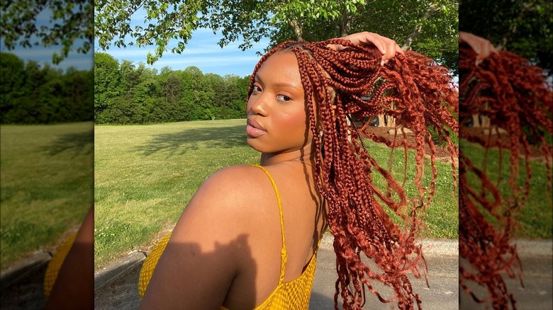 Woman with strawberry-colored box braids looking over her shoulder