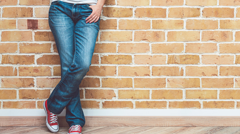 Person standing against brick wall in bootcut jeans