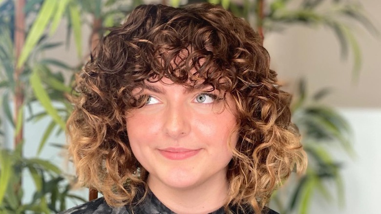 Woman posing with short coiled bronze hair