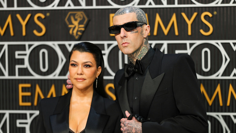 Kourtney Kardashian and Travis Barker pose in black suits