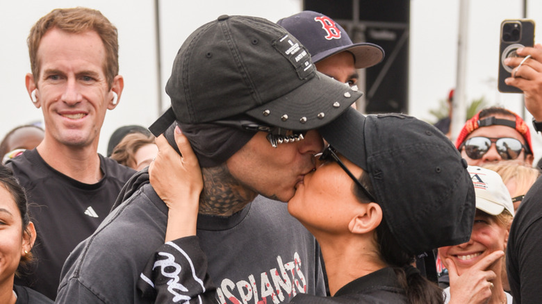 Travis Barker and Kourtney Kardashian kiss while wearing caps and sunglasses