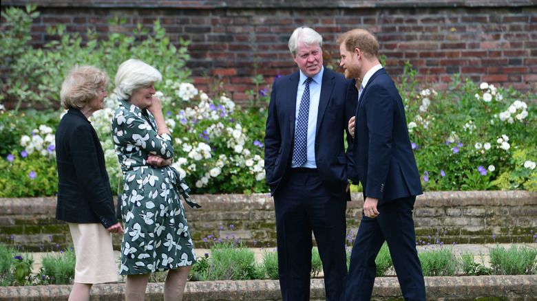 Prince Harry converses with Lady Sarah McCorquodale and Lady Jane Fellowes in a garden