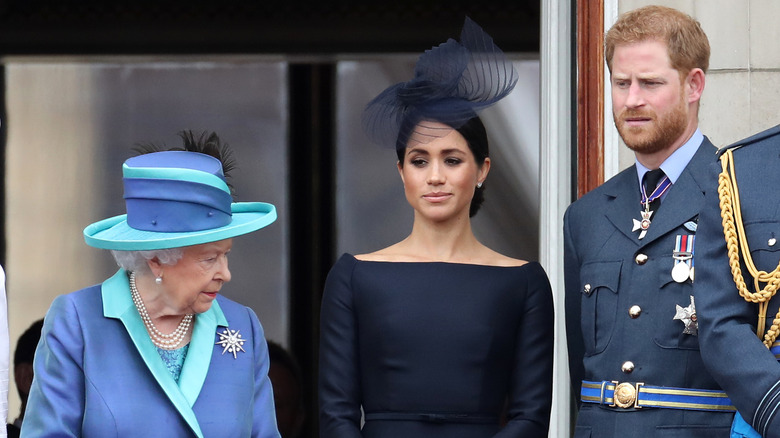 Queen Elizabeth II stands next to Meghan Markle and Prince Harry