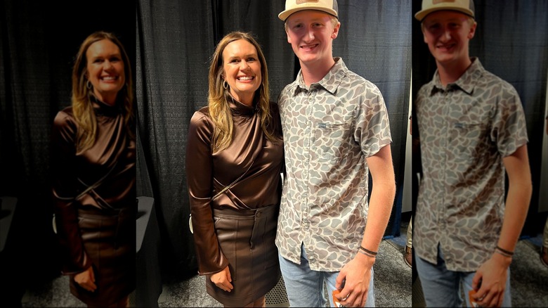 Sarah Huckabee Sanders posing with a fan in front of a gray curtain; she's wearing a brown leather skirt and a shiny brown blouse.