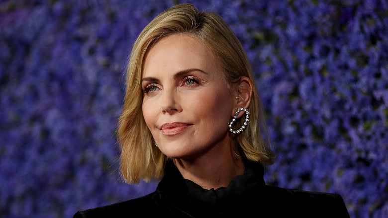 Charlize Theron by a purple backdrop