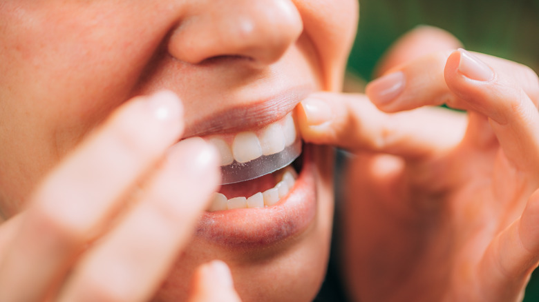 woman applying teeth whitening strips