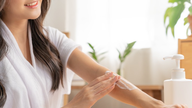 woman rubbing cream on arm