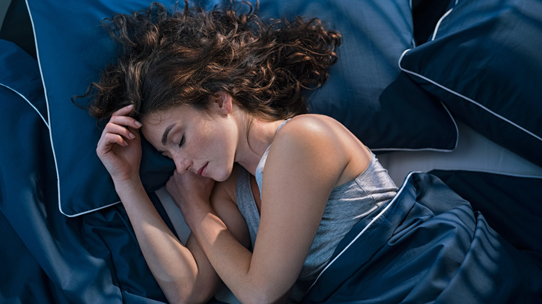Woman sleeping on bed with royal blue sheets and pillow covers