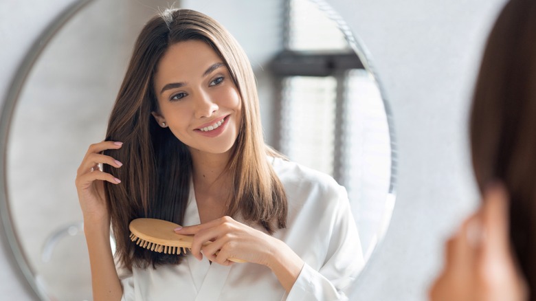 woman brushing her hair in front of the mirror