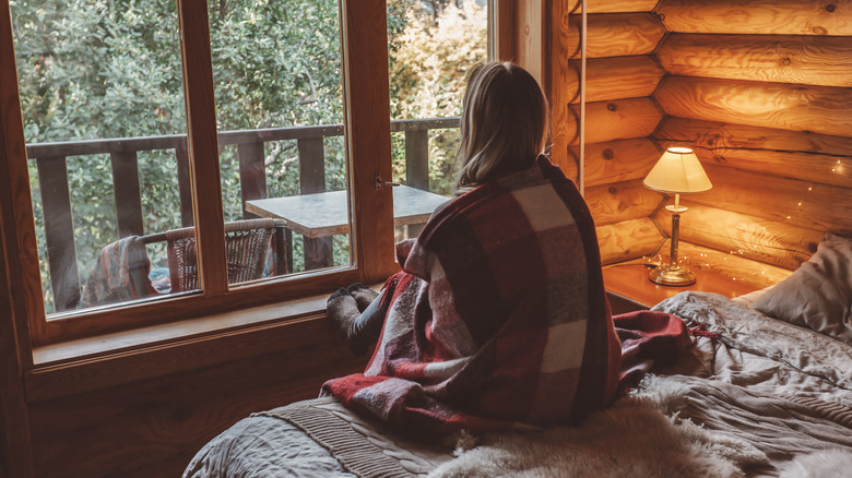 woman looking out window of tiny cabin