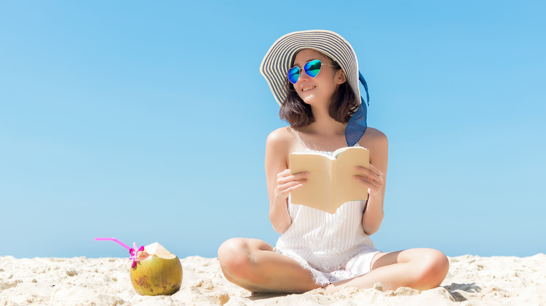 woman sitting on the beach reading a book