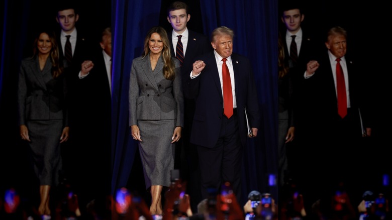 Melania Trump, Donald Trump, and Barron Trump walking on a stage, with Melania wearing a gray skirt and jacket.