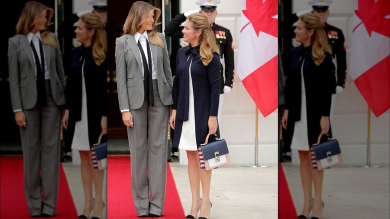 Melania Trump standing next to Sophie Trudeau, Trump in a gray pantsuit and tie.