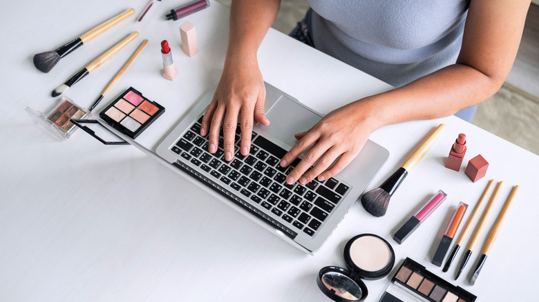 person working on laptop with makeup