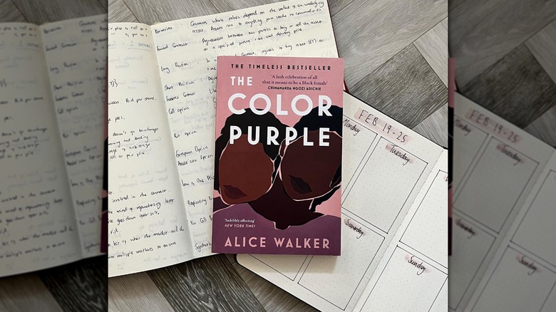 The Color Purple laying atop open journals