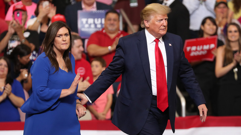 President Donald Trump walks on stage with Sarah Huckabee Sanders