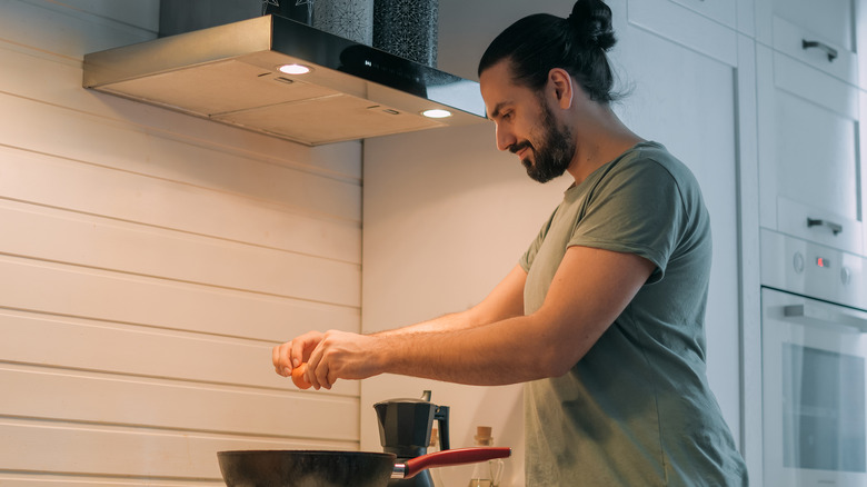 man with bun cooking eggs 