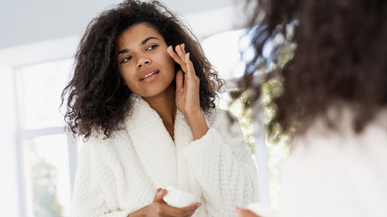 Young woman applying moisturizer