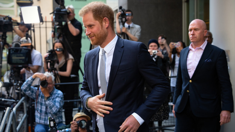 Prince harry smiling while walking past paparazzi