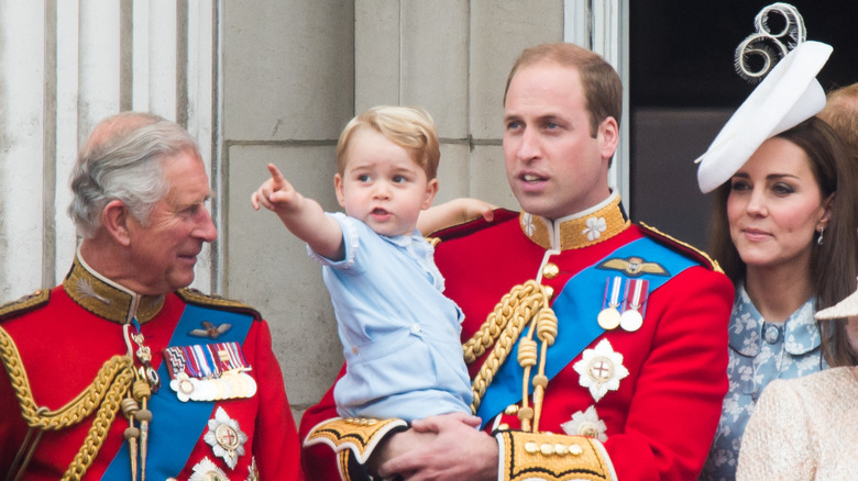 King Charles looking at Prince William holding his son with Kate Middleton