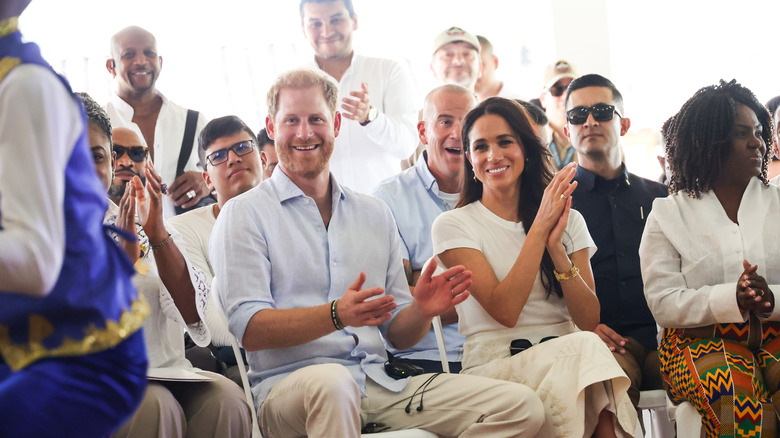 Prince Harry smiles sitting next to his wife, Meghan Markle