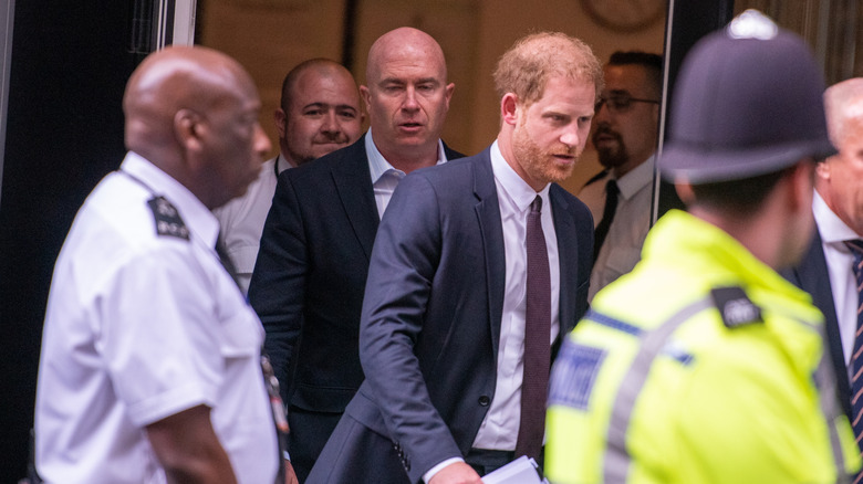 Prince Harry walks and several men stand near him